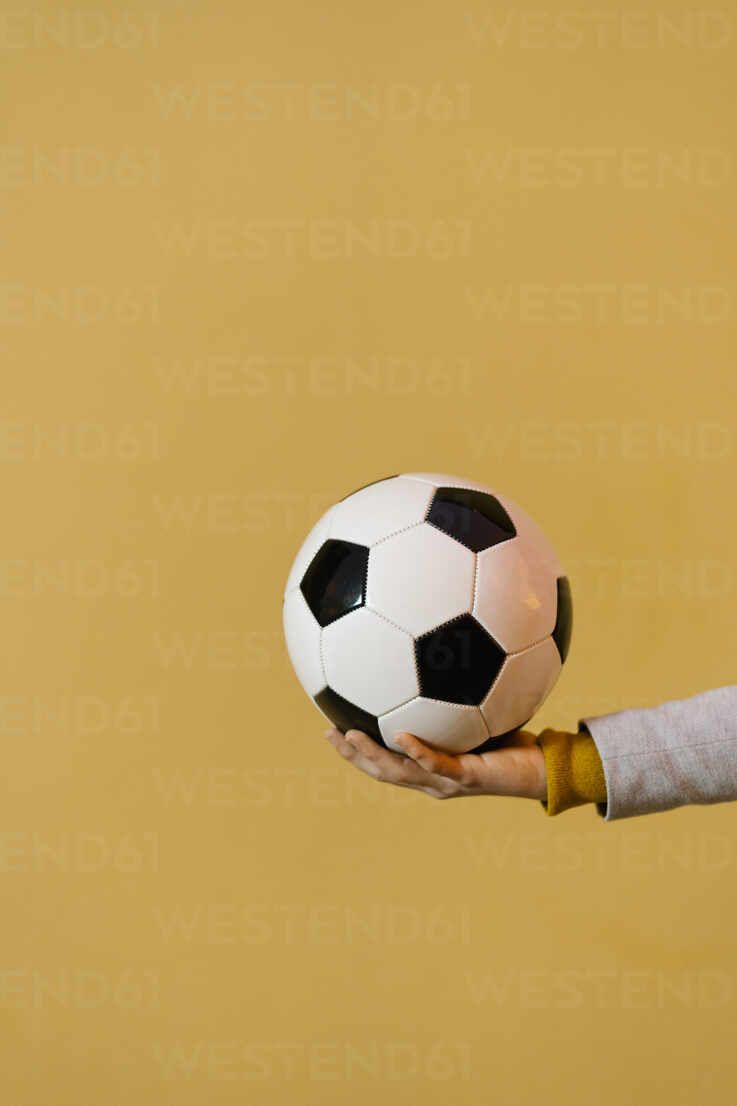  Fussball Hintergrundbild 737x1106. Mann hält Fußball gegen gelbe Wand, lizenzfreies Stockfoto