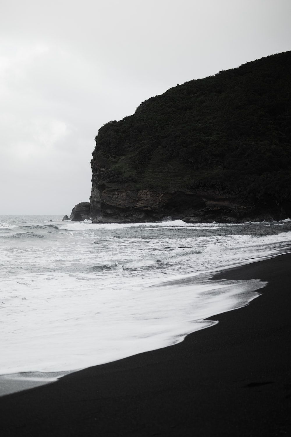  Fels Hintergrundbild 1000x1500. Foto Zum Thema Ein Schwarz Weiß Foto Eines Strandes Mit Einer Klippe Im Hintergrund