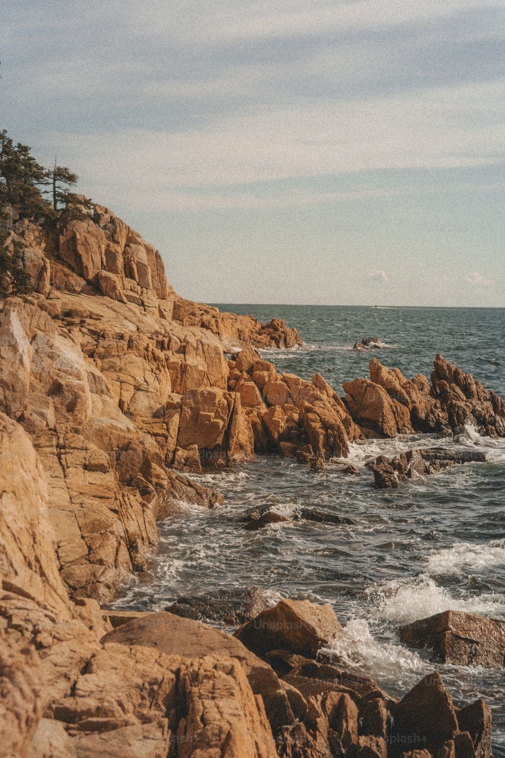  Fels Hintergrundbild 1000x1500. Foto zum Thema Ein felsiger strand mit wellen, die gegen ihn prallen