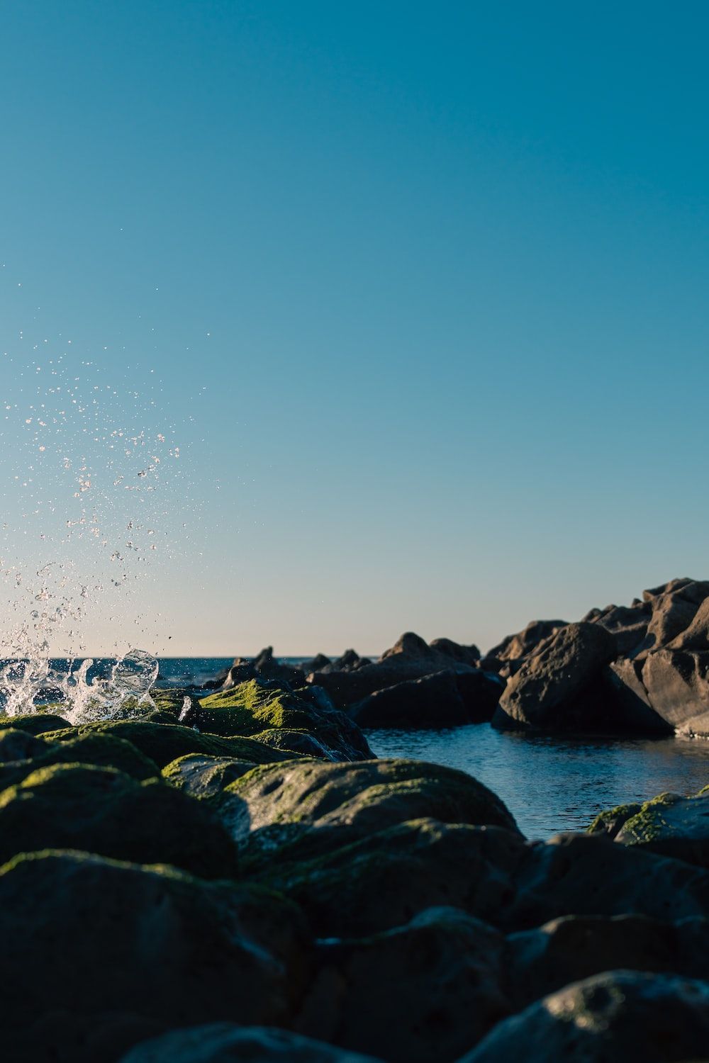  Fels Hintergrundbild 1000x1500. Foto zum Thema Eine person auf einem surfbrett im wasser in der nähe von felsen