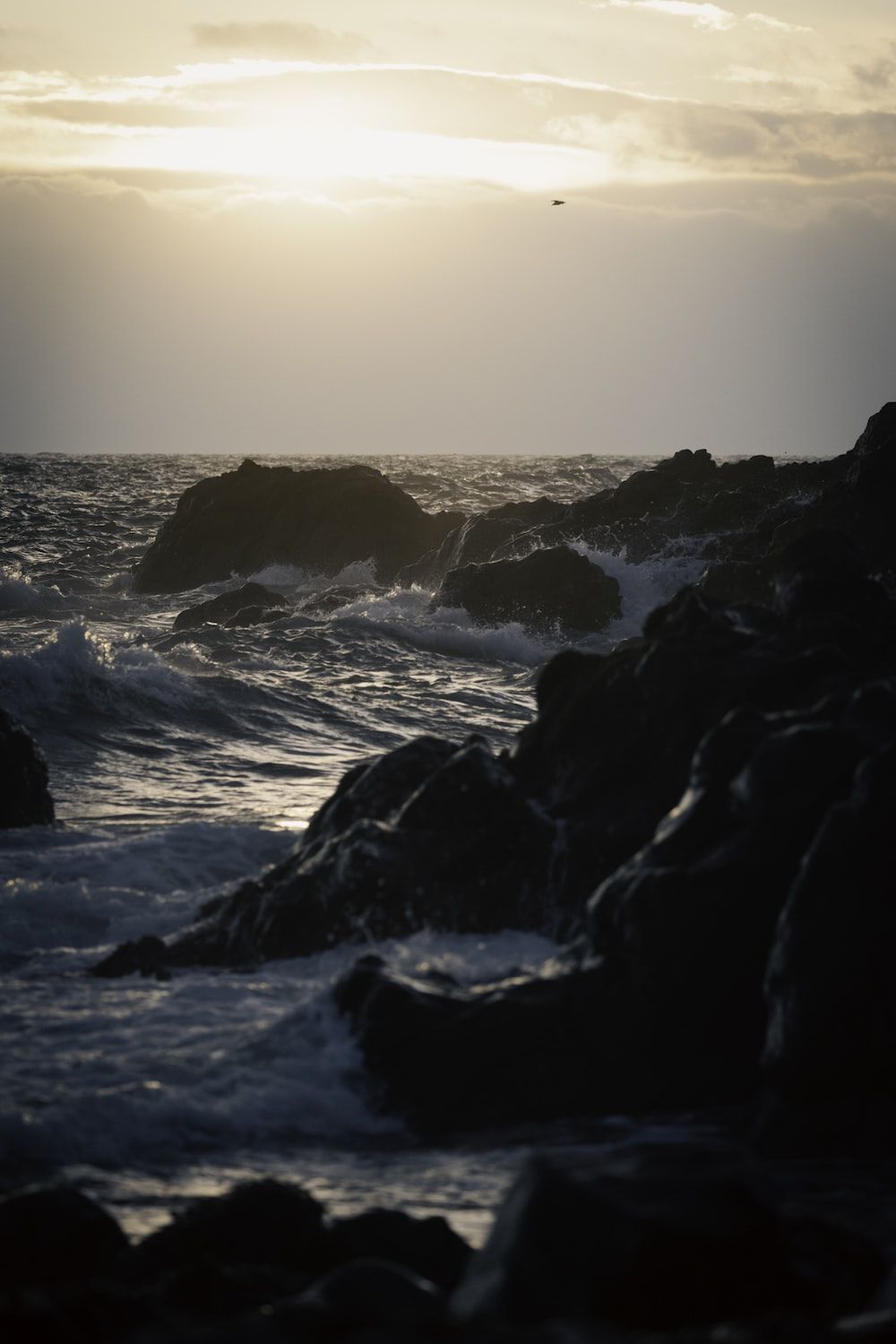  Felsen Hintergrundbild 1000x1500. Foto zum Thema Die Sonne geht über dem Meer und den Felsen unter