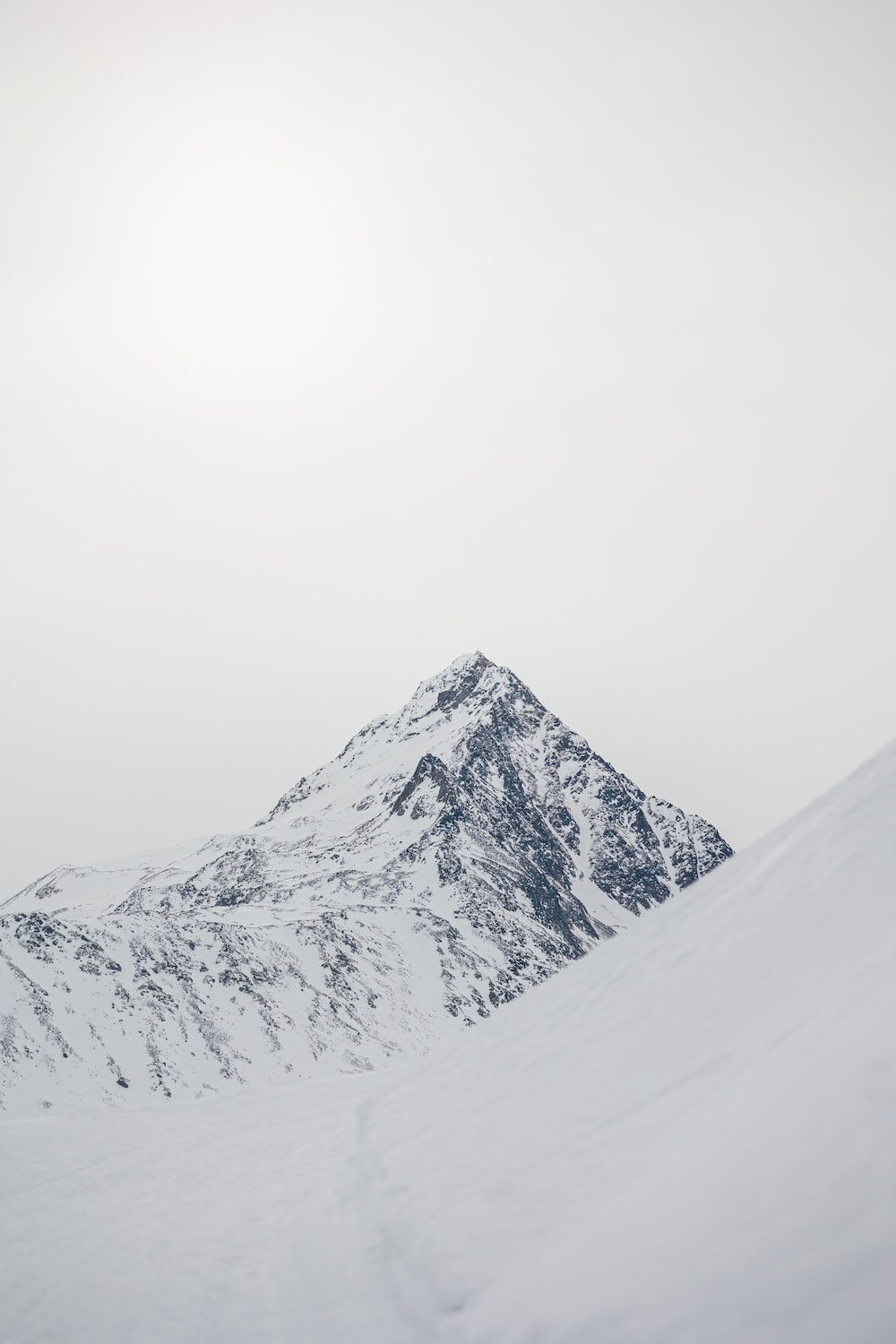  Berge Winter Hintergrundbild 1000x1500. Foto zum Thema Eine Person, die einen schneebedeckten Berg hinunterfährt