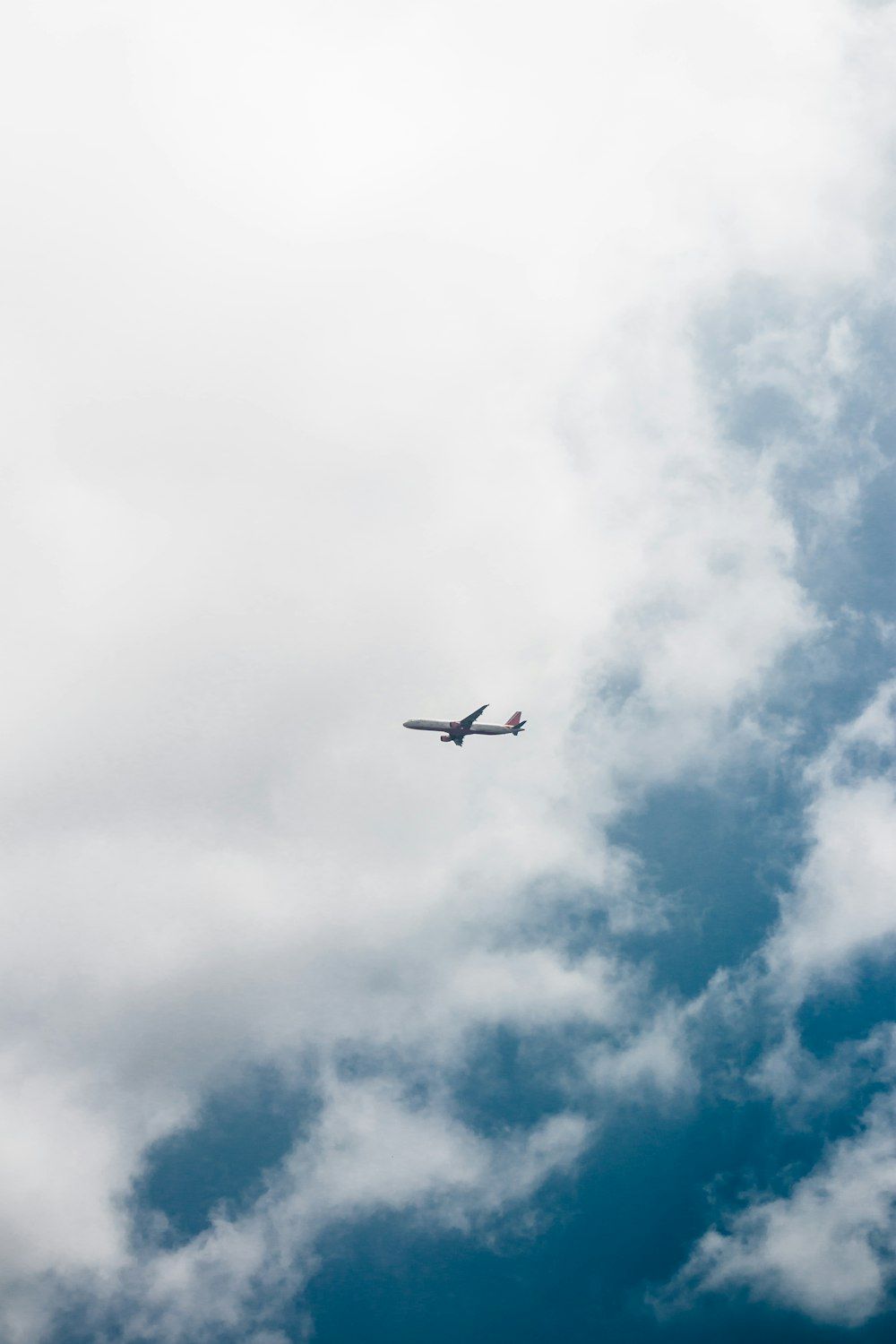  Flugzeug Hintergrundbild 1000x1500. Foto zum Thema Ein Flugzeug, das durch einen bewölkten blauen Himmel fliegt